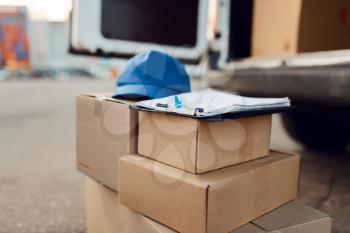 Parcel boxes and cap with notebook, delivery service concept, delivering business, nobody. Cardboard packages, deliver, courier or shipping job