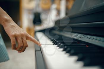 Young woman choosing digital piano in music store. Assortment in musical instrument shop, female musician buying equipment