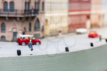 Male person with briefcase walking on pier, miniature scene outdoor, europe. Mini figures with high detaling of objects, realistically diorama
