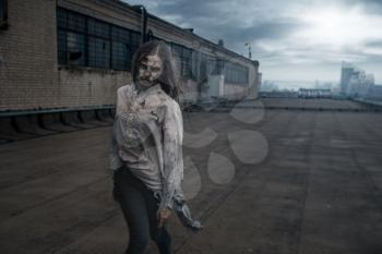 Scary female zombie on the roof of abandoned building, deadly chase. Horror in city, creepy crawlies attack, apocalypse