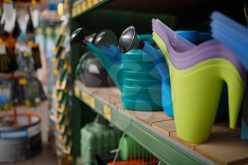 Watering cans assortment on the shelf, shop for floristry, nobody. Equipment in store for floriculture, florist instrument choice, gardening hobby tools
