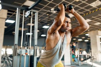 Muscular athlete in sportswear at exercise machine in motion on training in gym. Workout in sport club, healthy lifestyle