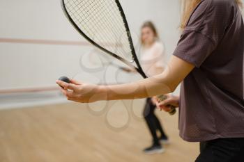 Two female players with squash rackets, focus on ball. Girls on training, active sport hobby, fitness workout for healthy lifestyle
