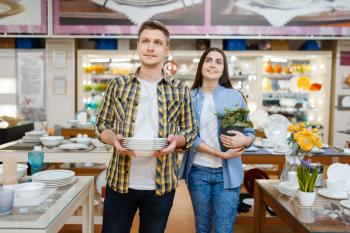 Young couple with plates in houseware store. Man and woman buying home goods in market, family in kitchenware supply shop