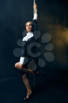 Sexy perverse nun in a cassock dances on a pole like a stripper, vicious desires. Corrupt sister in the monastery, sinful religious people