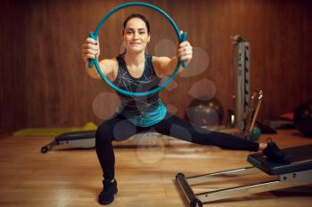 Sporty woman in sportswear, pilates training with ring on exercise machine in gym. Fitness workuot in sport club. Athletic female person, aerobics indoor, body stretching