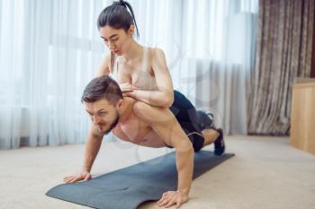 Morning fitness training of love couple at home. Active man and woman in sportswear doing push up exercise in their house, healthy lifestyle, physical culture