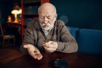 Pour elderly man holds some coins