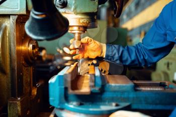 Male technician in uniform and helmet works on lathe, plant. Industrial production, metalwork engineering