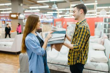 Young love couple choosing texture of mattress in furniture store showroom. Man and woman looking samples for bedroom in shop, husband and wife buys goods for modern home interior