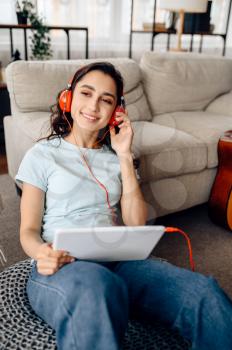 Cute woman in headphones enjoys listen to music. Pretty lady in earphones relax in the room, female sound lover resting