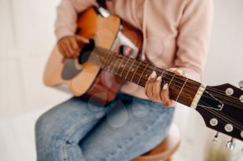 Woman play the guitar at home, closeup view. Pretty lady with musical instrument relax in the room, female music lover resting