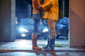 Love couple dating in night park, summer rainy day. Man and woman in rain, romantic date on walking path, wet weather in alley