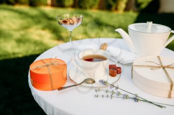 Table setting, romantic tea party with sweets, top view, nobody. Luxury silverware on white tablecloth, tableware outdoors. Wedding celebration on summer meadow