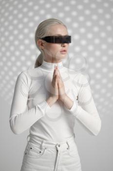Young woman in white clothes and futuristic glasses, light grey background. Female person in virtual reality style, future technology, futurism concept