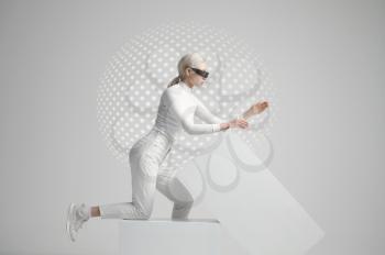 Model in white clothes and futuristic glasses lying on cubes, light grey background. Female person in virtual reality style, future technology, futurism concept