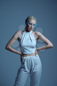Sexual futuristic woman in white clothes and modern glasses, grey background. Sexy female person in virtual reality style, future technology, futurism