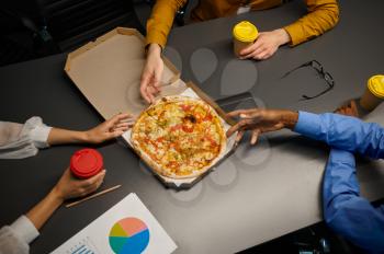 Team of managers eats pizza, business lunch in IT office. Professional teamwork and planning, group brainstorming and corporate work, modern company interior on background