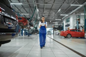 Female mechanic with laptop, car service, professional diagtostic. Vehicle repairing garage, woman in uniform, automobile station interior on background