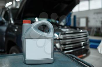 Oil canister on toolbox, car service concept, nobody. Vehicle repairing garage, automobile with opened hood on background, auto station interior, high-quality parts and consumables
