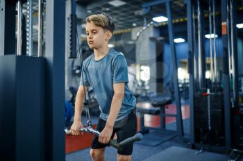 Boy on exercise machine, active training in gym. Youngster in sport club, healthcare and healthy lifestyle, schoolboy on workout, sportive youth