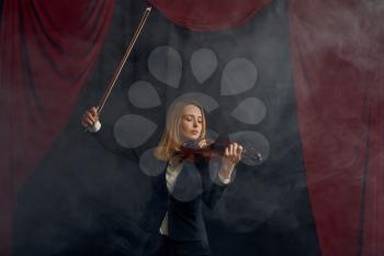 Female violonist with bow and violin, solo concert on stage. Woman with string musical instrument, music art, musician play on viola, dark background