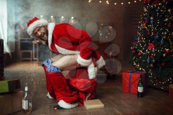 Bad Santa claus pooping in gift box, nasty party, humor. Unhealthy lifestyle, bearded man in holiday costume, new year and alcoholism