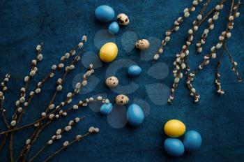 Willow branch and easter eggs on blue cloth background. Spring tree blooming and paschal food, fresh floral decoration for holiday celebration, event symbol