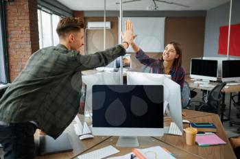 IT specialists high-five each other in office. Web programmer or designer at workplace, creative occupation. Modern information technology, corporate team