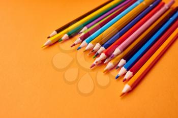 Set of colorful pencils closeup, orange background. Office stationery supplies, school or education accessories, writing and drawing tools