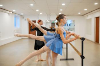 Master works with young ballerinas at the barre in class. Ballet school, female dancers on choreography lesson, girls practicing grace dance