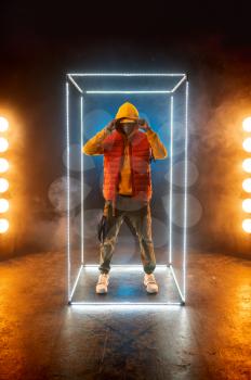 Stylish rapper poses in illuminated cube. Hip-hop performer, rap singer, break-dance performing, entertainment lifestyle