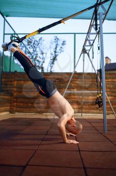Sportive man doing exercise with ropes on sports ground outdoors. Slim female person in sportswear, outside fitness training, fit workout