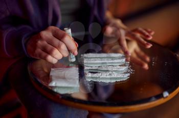 Drug addict woman with powder prepares a dose, shebang interior on background, den. Narcotic addiction problem, eternal depression of junky people