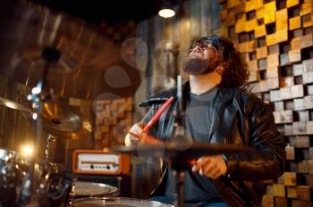 Brutal drummer behind the drum kit, music performing on stage. Rock band performance or repetition in garage, man with musical instrument, live sound performer