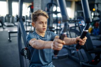 Boy on exercise machine, fit training in gym. Youngster in sport club, healthcare and healthy lifestyle, schoolboy on workout, sportive youth