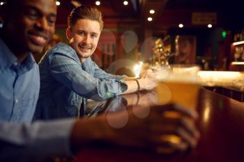 Two male friends leisures at the counter in bar. Group of people relax in pub, night lifestyle, friendship, event celebration