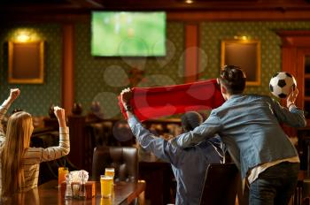 Football fans with red scarf watching game translation, friends in bar. Group of people relax in pub, night lifestyle, friendship, sport celebration