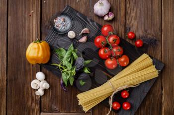 Fresh vegetables and spaghetti on wooden background. Organic vegetarian food, grocery assortment, natural products, healthy lifestyle concept