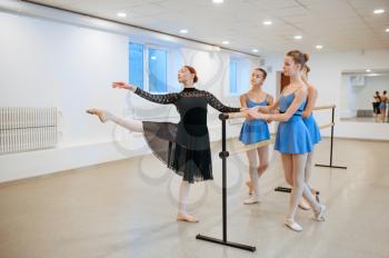 Master and young ballerinas exercise at the barre in class. Ballet school, female dancers on choreography lesson, girls practicing grace dance