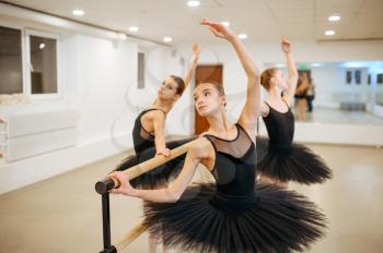 Three young ballerinas, teens rehearsal at the barre in class. Ballet school, female dancers on choreography lesson, girls practicing grace dance