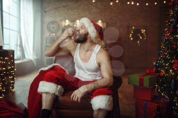 Bad Santa claus puts out cigar on his tongue, nasty party, humor. Unhealthy lifestyle, bearded man in holiday costume, new year and alcoholism