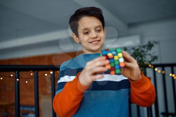 Smiling boy holds puzzle cube in his hands. Toy for brain and logical mind training, creative game, solving of complex problems