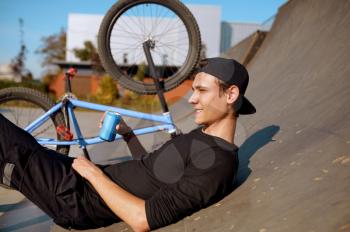 Young male bmx biker leisures on ramp,teenager on training in skatepark. Extreme bicycle sport, dangerous cycle exercise, risk street riding, biking in summer park