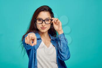 Attractive young woman in glasses, blue background, positive emotion. Face expression, female person looking on camera in studio, emotional concept, feelings