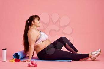 Overweight woman doing abs exercise, body positive, pink background. Obesity fighting, striving for a healthy lifestyle
