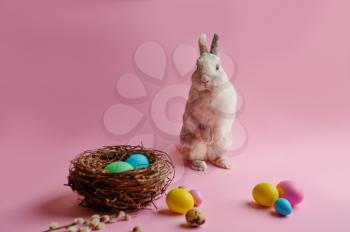 Colorful easter eggs and rabbit on pink background. Paschal food, event decoration, spring holiday celebration symbol
