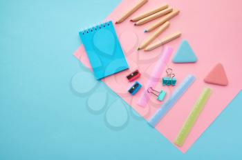 Office stationery supplies, blue and pink background. School or education accessories, writing and drawing tools, pencils and rubbers, ruler and paper clips