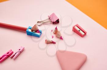 Pencil and sharpener on pink paper sheet, orange background. Office stationery supplies, school or education accessories, writing and drawing tools