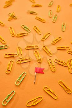 Paper clips closeup on orange background. Office stationery supplies, school or education accessories, writing and drawing tools